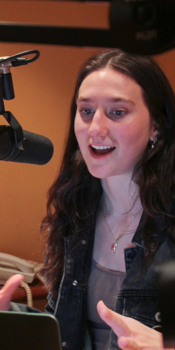 A woman speaks into a microphone in a recording room